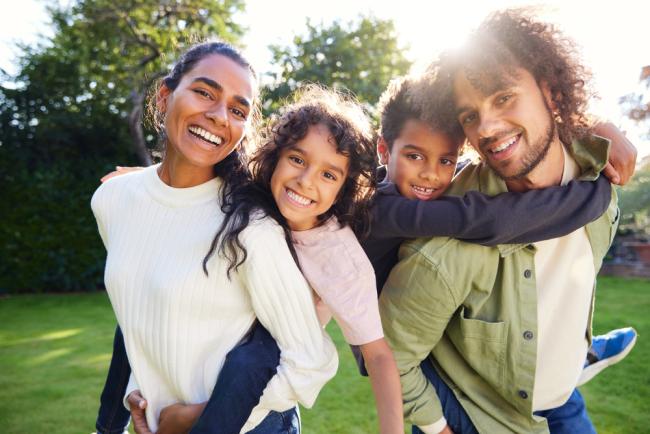 Parents giving their kids piggybacks, waist up, close up smiling at camera