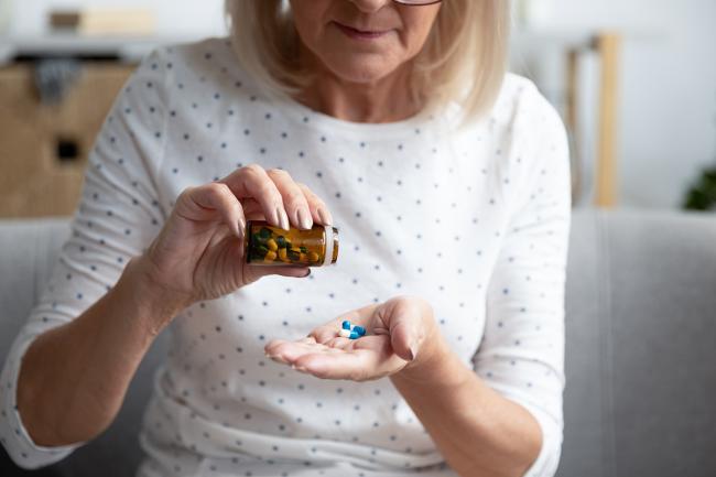 A woman taking pills from a bottle.