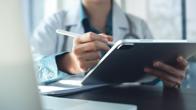 Image of a medical professional using a tablet and a stylus 