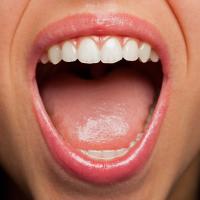 A close-up of a woman's open mouth showing her teeth and tongue.